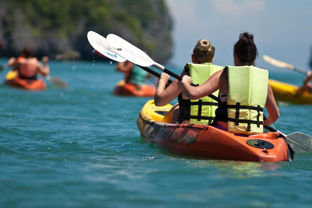 two women paddling in sea wearing yellow kayak life vests