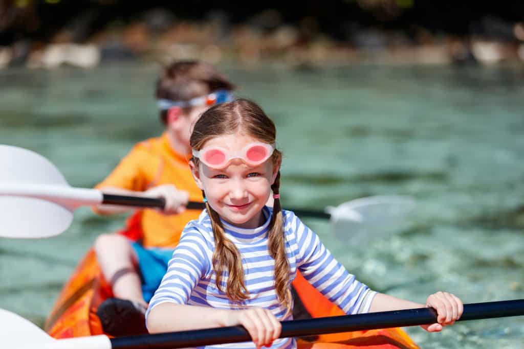 two young kids kayaking wearing swimming goggles