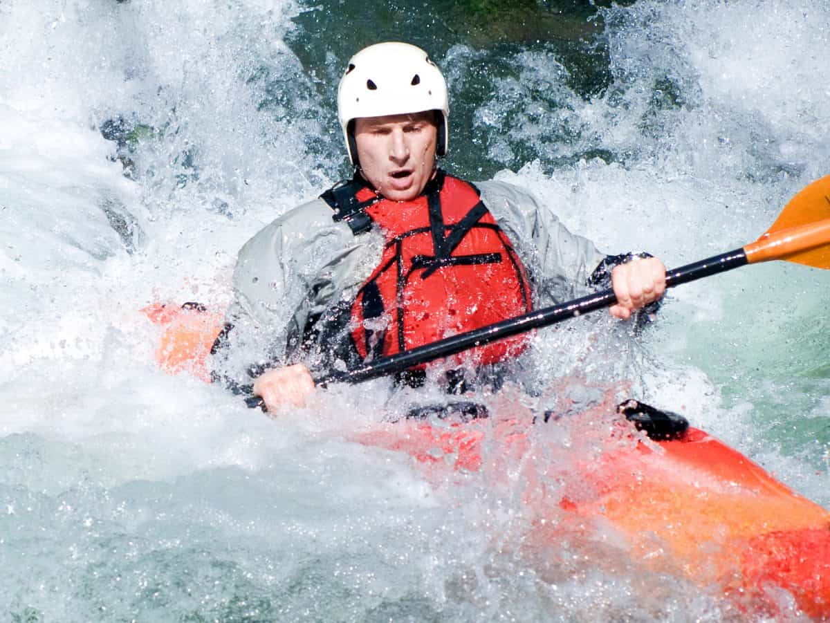 Man in orange kayak being swapped by rapids