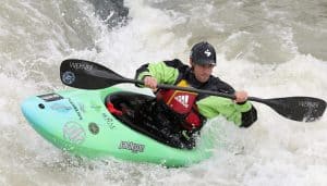 man fights whitewater rapids in green playboat