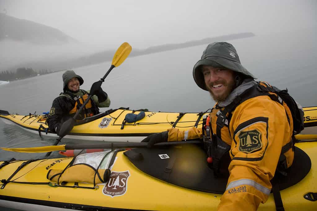 Forest Service personnel kayaking in heavy rain wear bright color clothes to stay visible