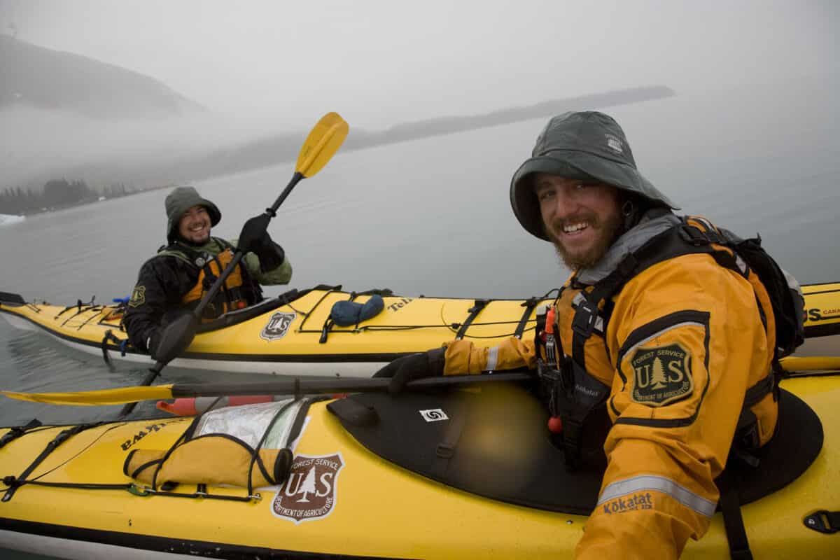 Forest Service personnel kayaking in heavy rain wear bright color clothes to stay visible 