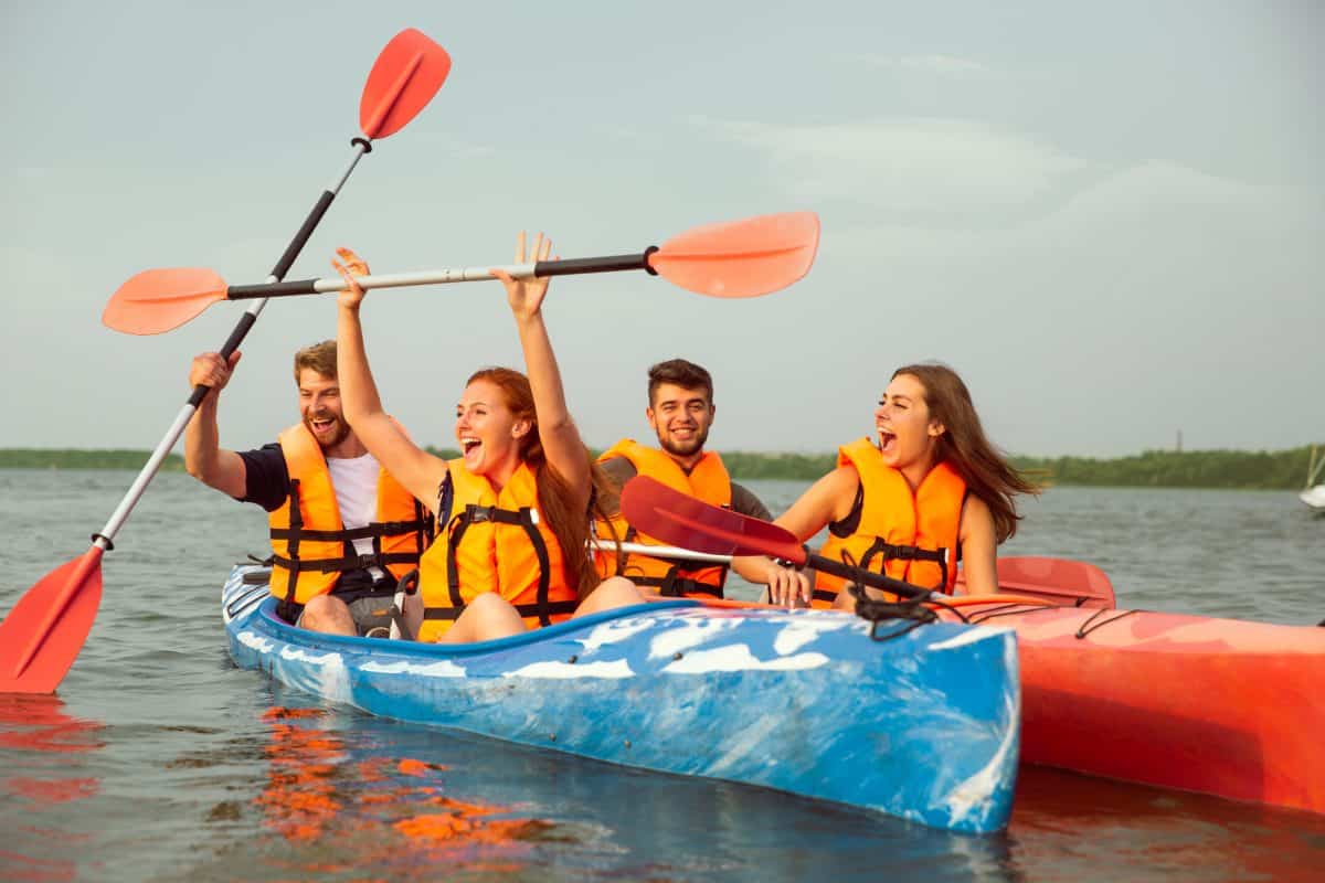 Friends kayaking on river in bright kayaks