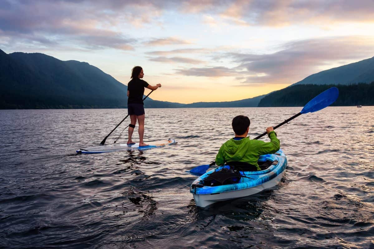 Friends on Scenic Lake Kayaking and Paddleboarding Together