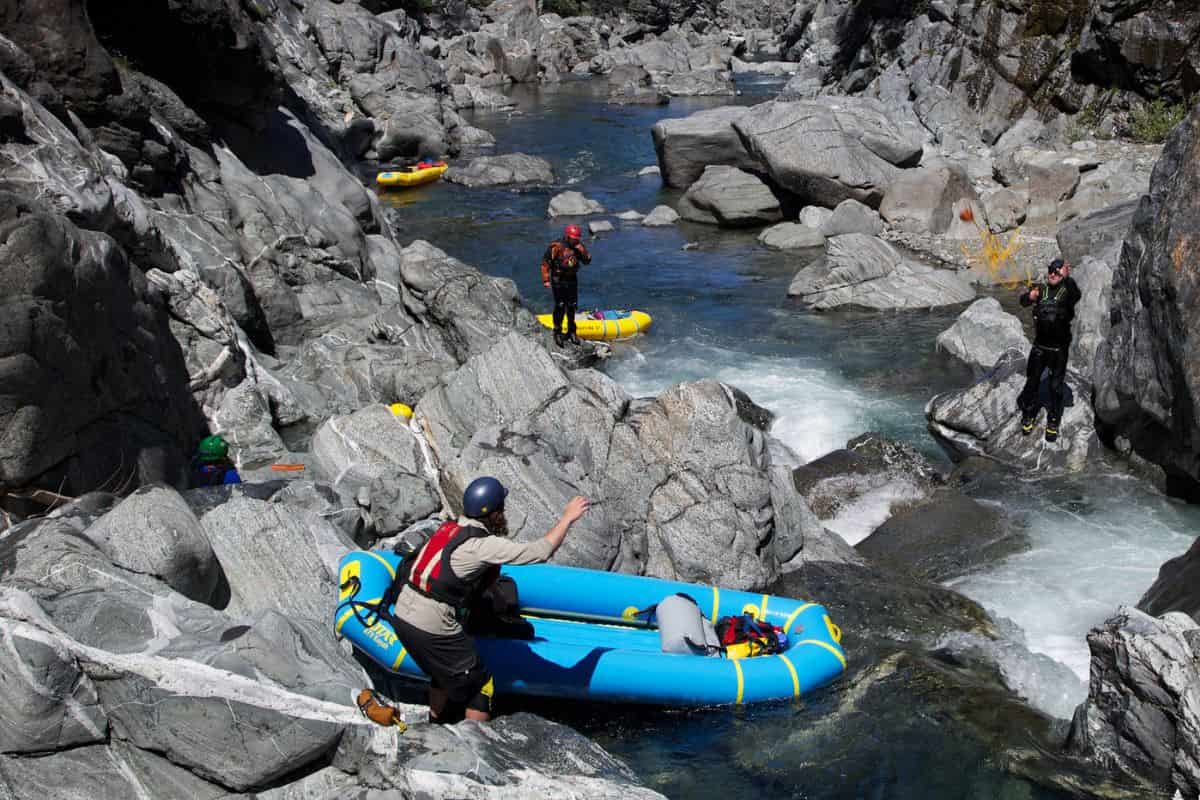 Group drag brightly colored inflatable boats over the rocks to the water