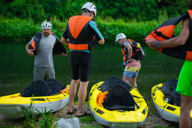 How To Get In And Out Of A Kayak - Group of students at a kayak school on the water's edge getting to to launch their recreational kayaks