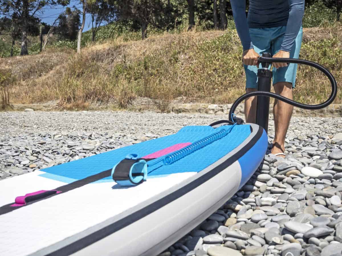 Guy pumping up inflatable SUP on beach