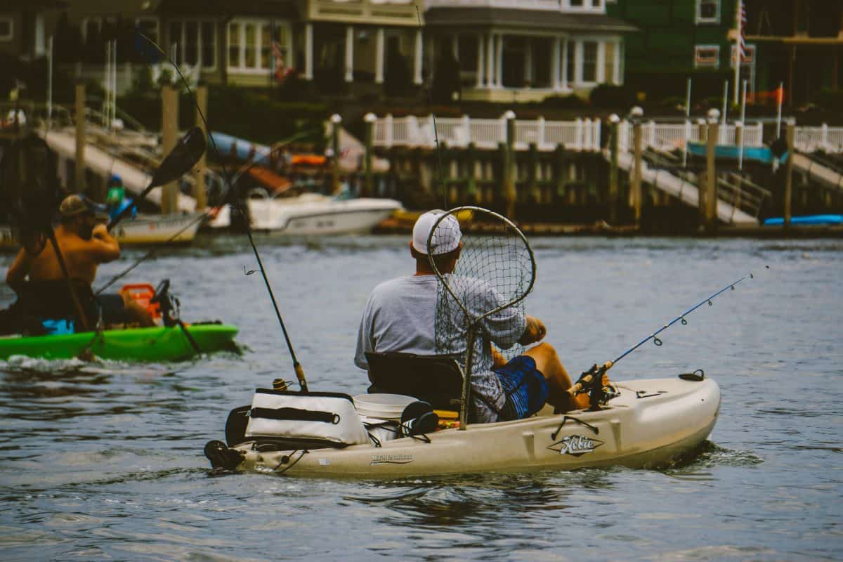 Man in fishing kayak pedalling down river