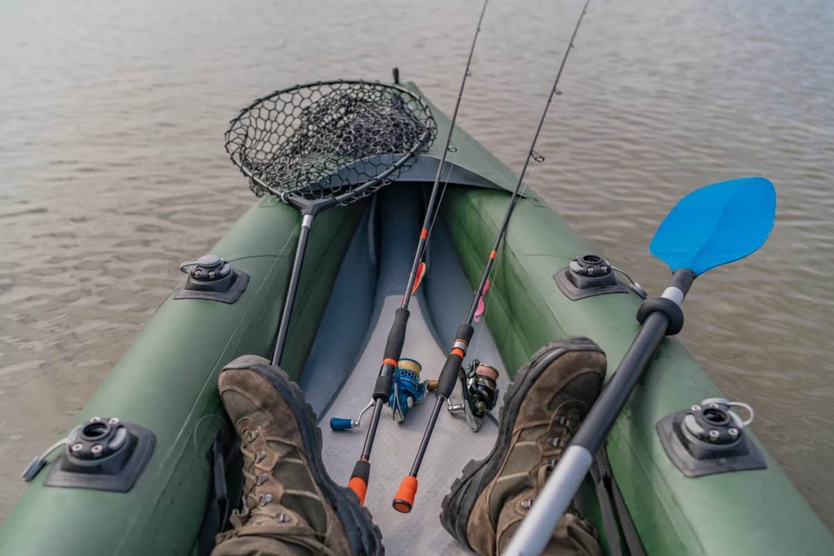 Angler in boat with rods and kayak fishing net
