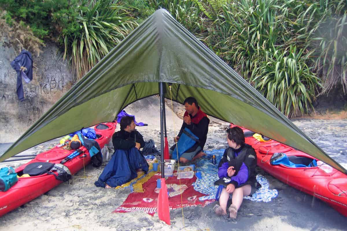 Kayakers sheltering under a tent to take a break from the rain