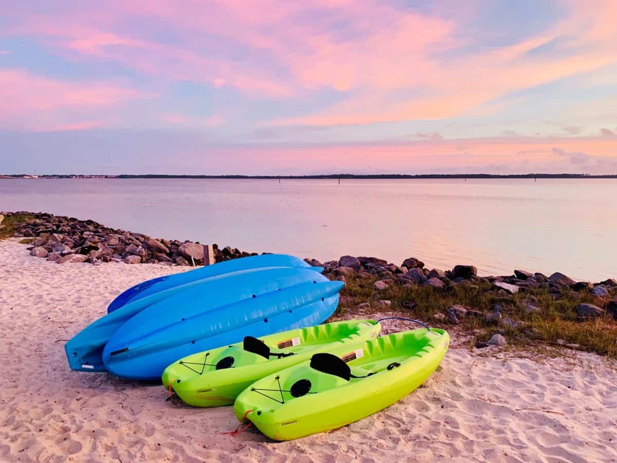 SIt on top kayaks on beach, two blue, two green, with kayak seat