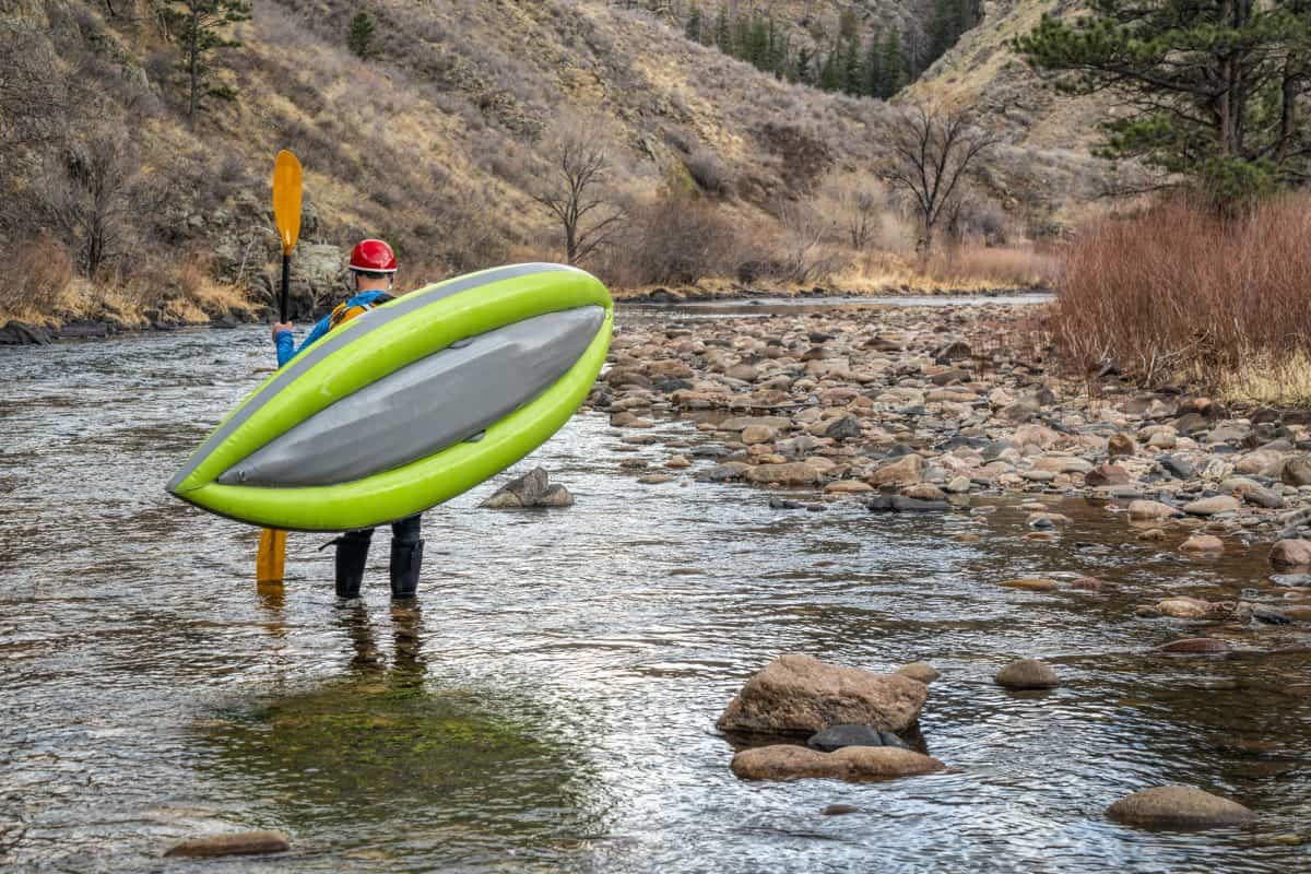 Male paddler carrying inflatable boat kayak