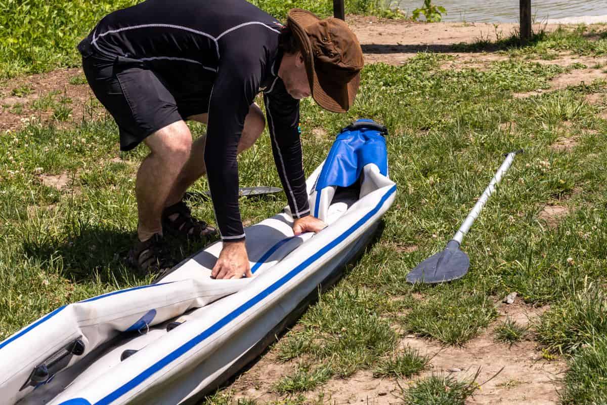 Man folding up deflated inflatable kayak.
