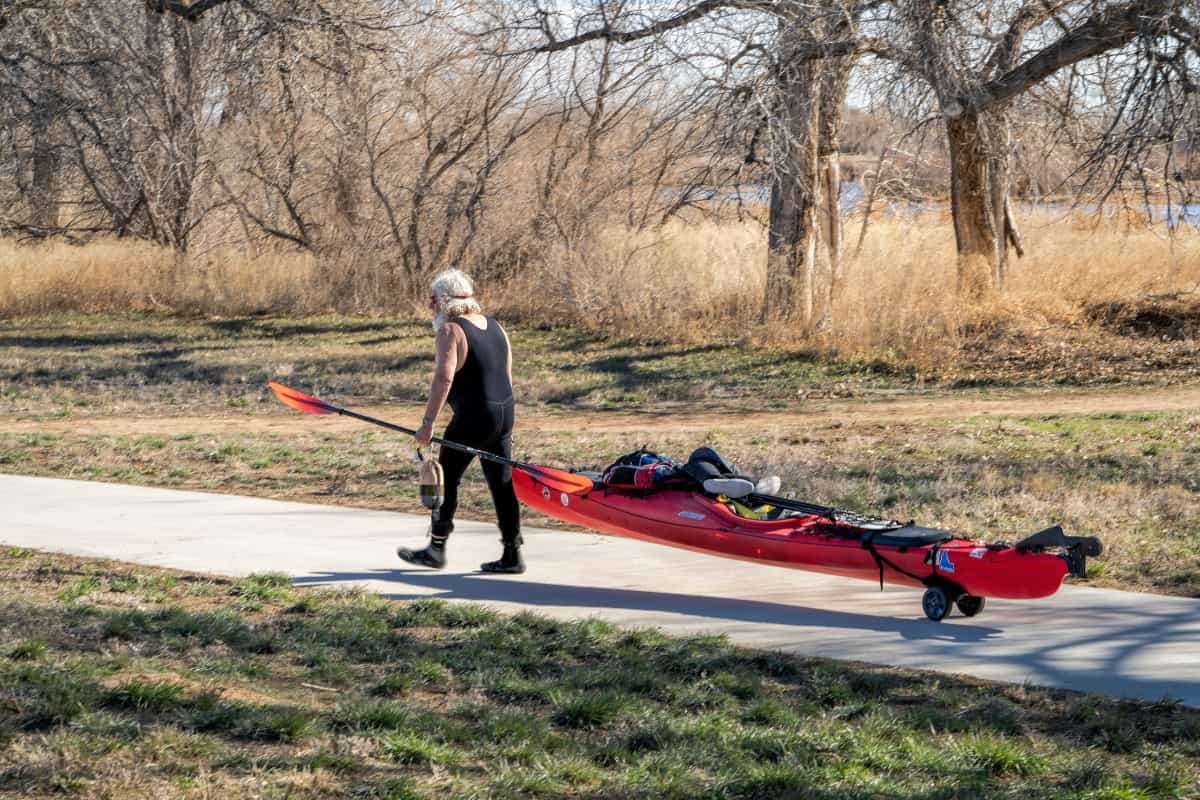 Man hauling red kayak using a cart