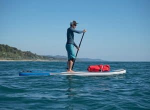 Man in blue waterproof swimsuit paddles SUP on Ocean