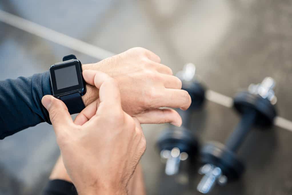 Man in gym using smart watch to track training for cold water kayaking