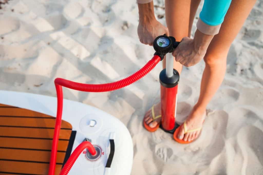 Man Inflating inflatable paddleboard on beach