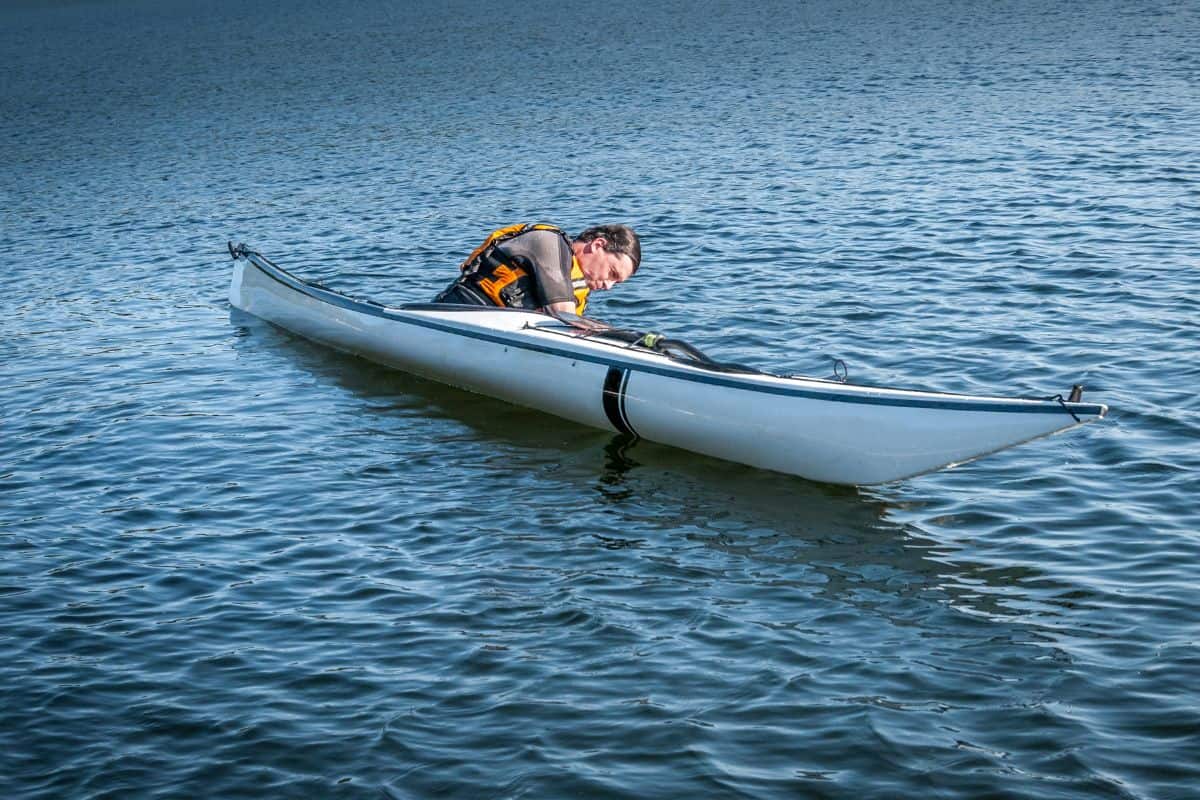 Man leaning forward in a kayak at the start of the wet exit process