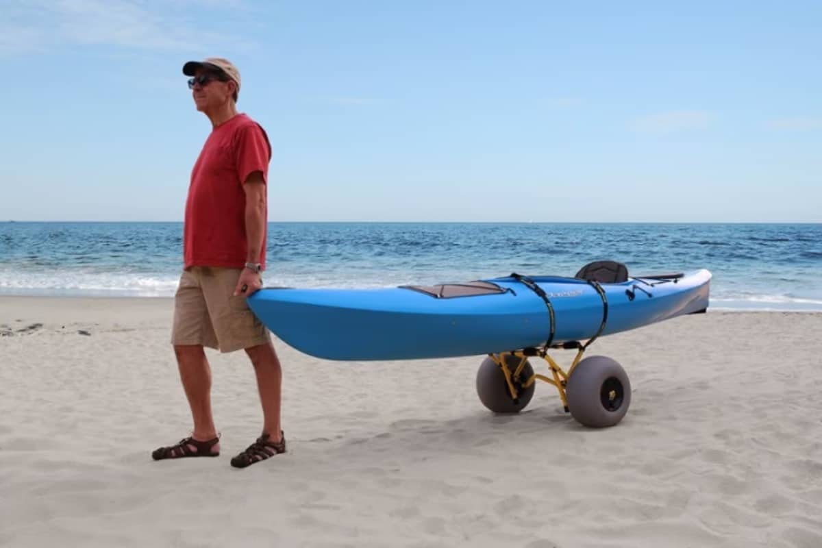 Man on beach pulling kayak trolly