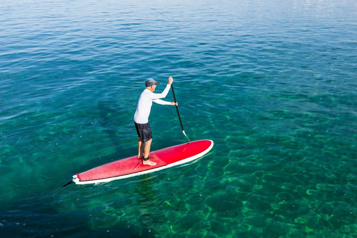 Man paddling a layered fiberglass paddle board