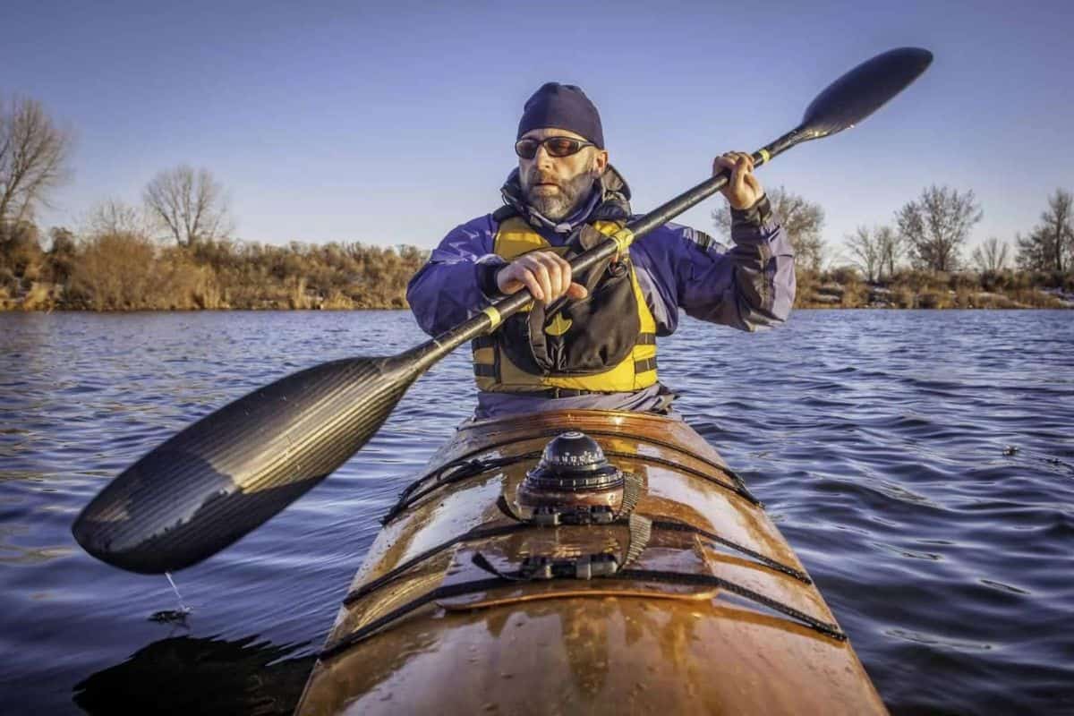 Man paddling kayak with deck mount compass on bow