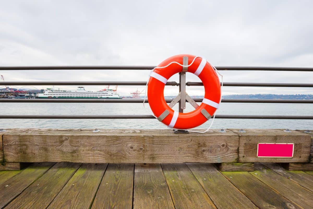 Orange buoy on railing by the sea