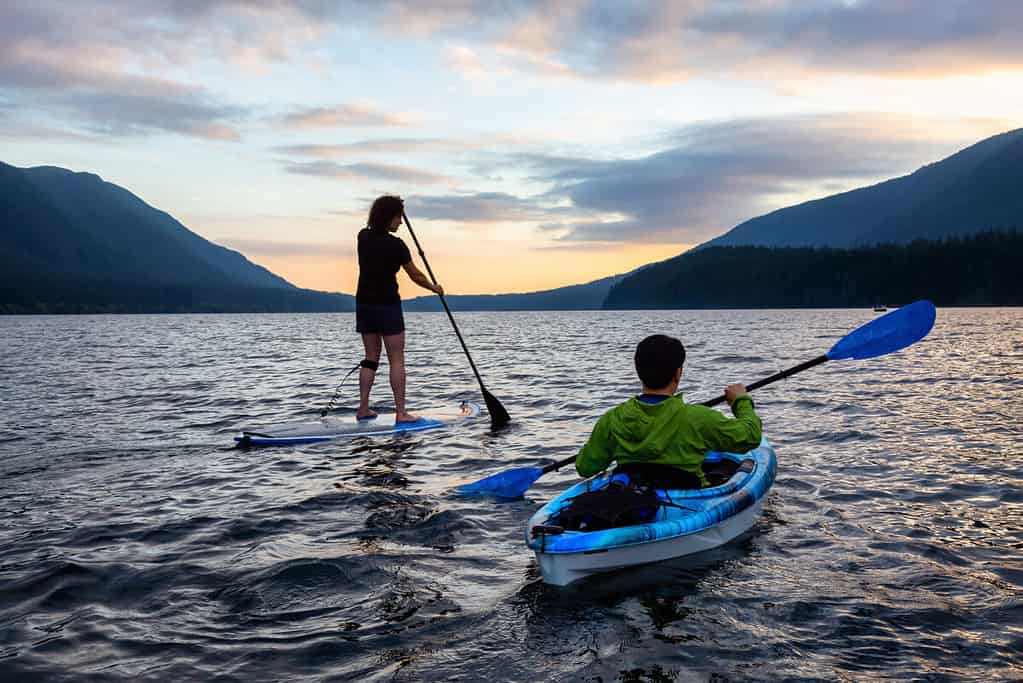 Paddle boarder and Kayaker out on the water together