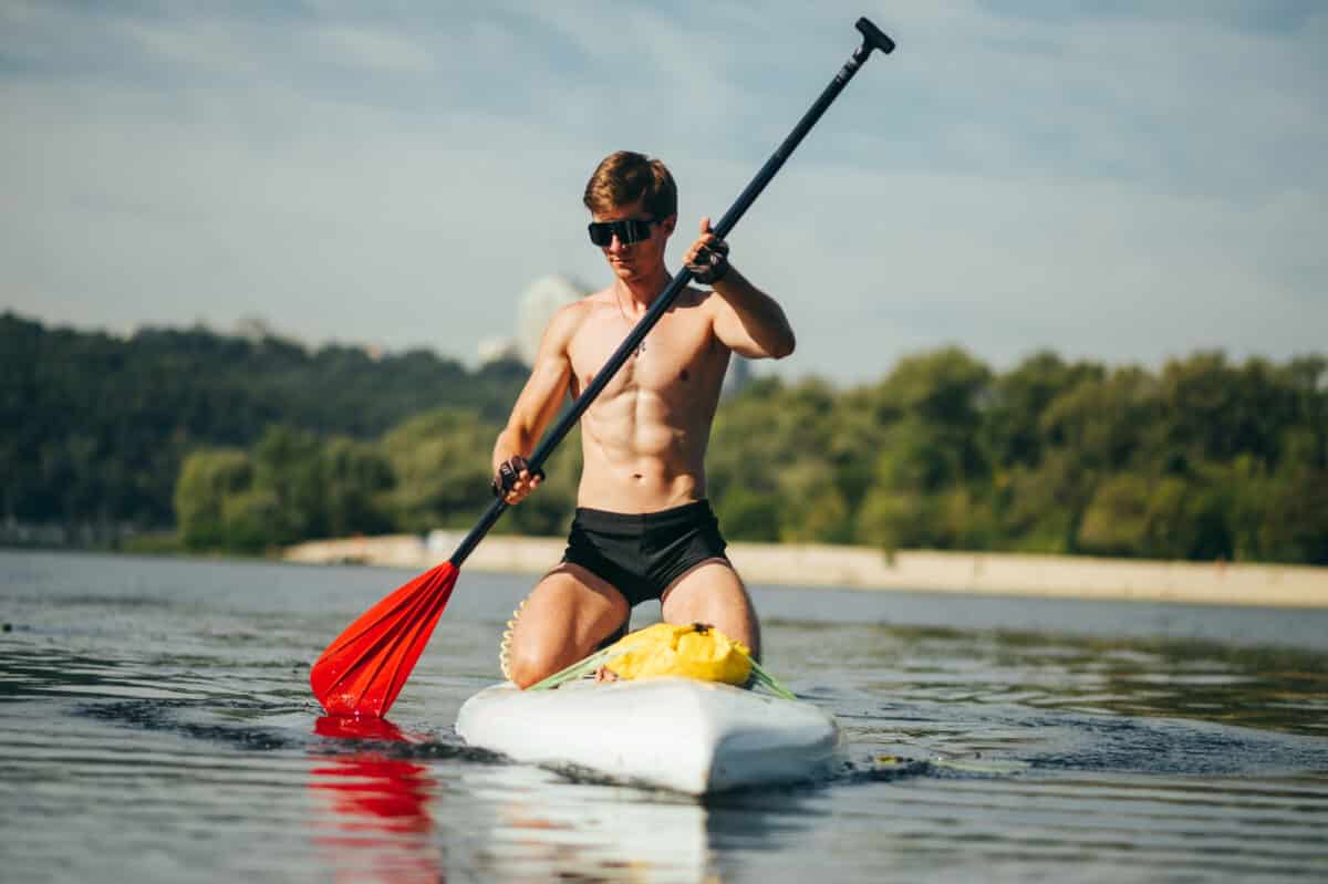 Sporty young man press paddle overheard on a sup board.
