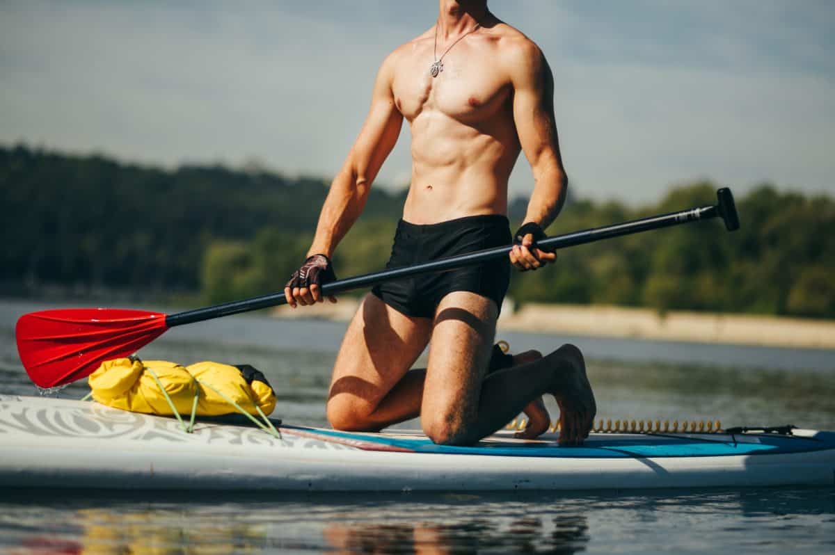 Sporty young man with a muscular torso on a sup board
