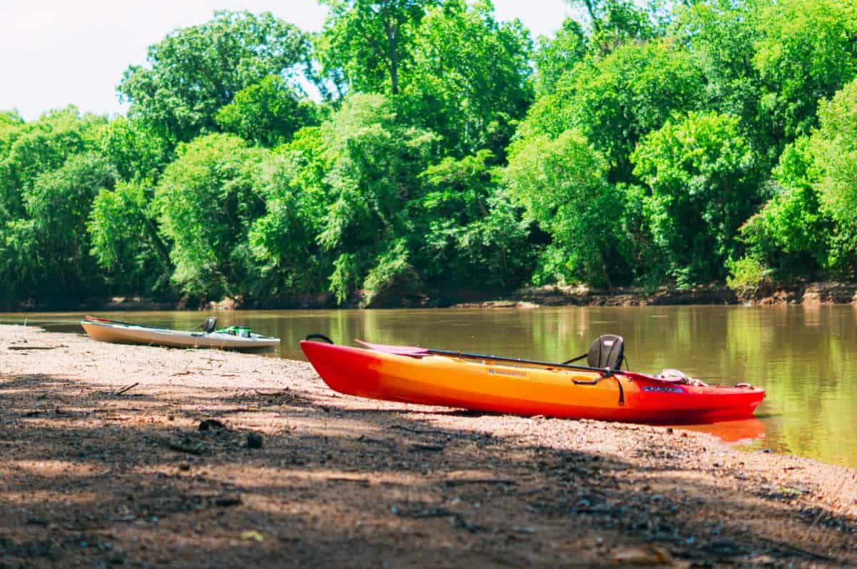 Oranage kayak on river shore with black kayak seat