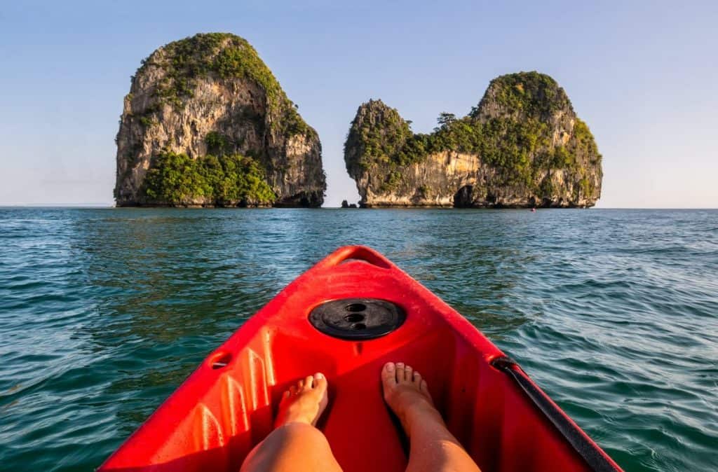 People of front of kayak in ocean of thailand, looking at to limestone rock