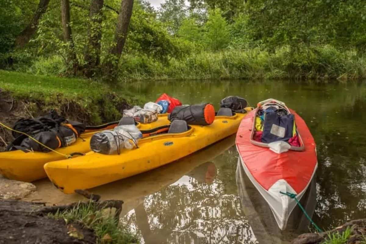 Two kayaks loaded with equipment on the banks of a river