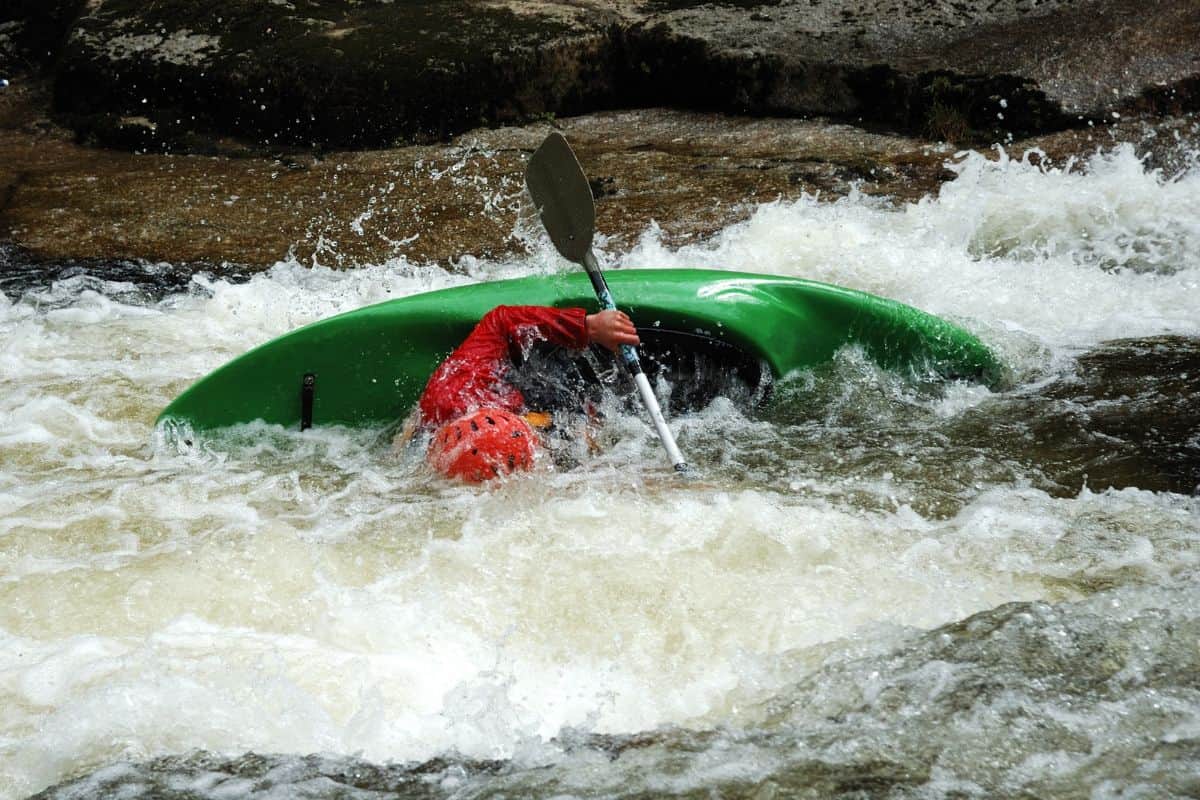 Whitewater kayaker about to preform a wet exit from his kayak