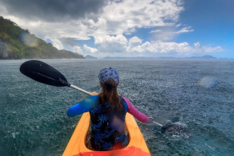 Woman,Paddling,A,Kayak,At,The,Rain,In,The,Island
