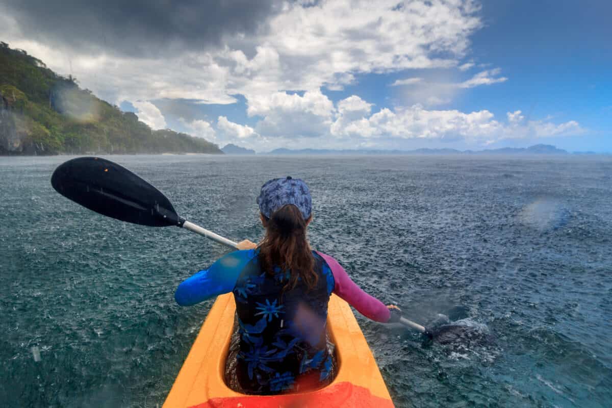 Woman,Paddling,A,Kayak,At,The,Rain,In,The,Island