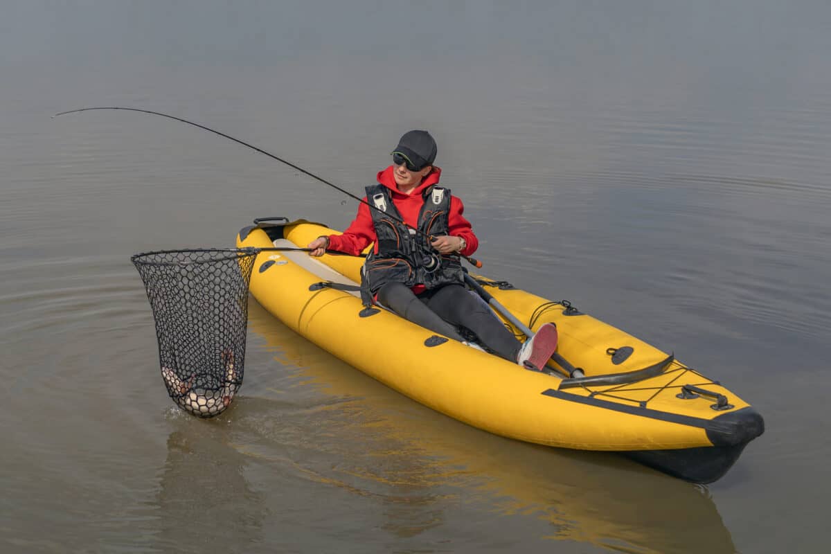 Women landing a fish from her bright yellow fishing kayaks