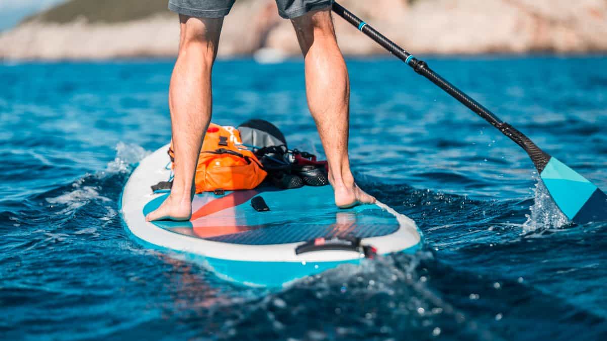 Young athletic man paddling on a SUP standup paddleboard