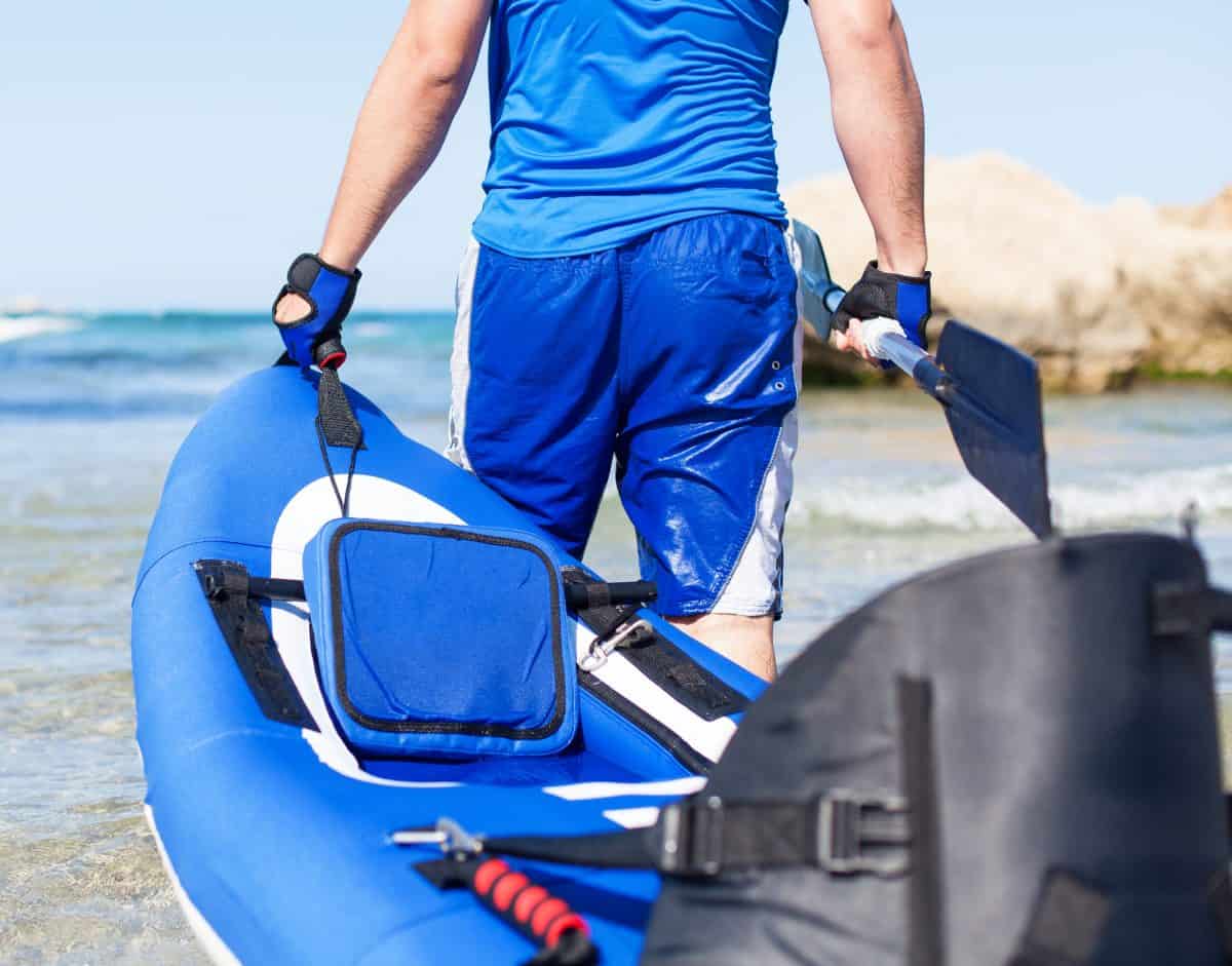 Young man carrying 2 person inflatable kayak